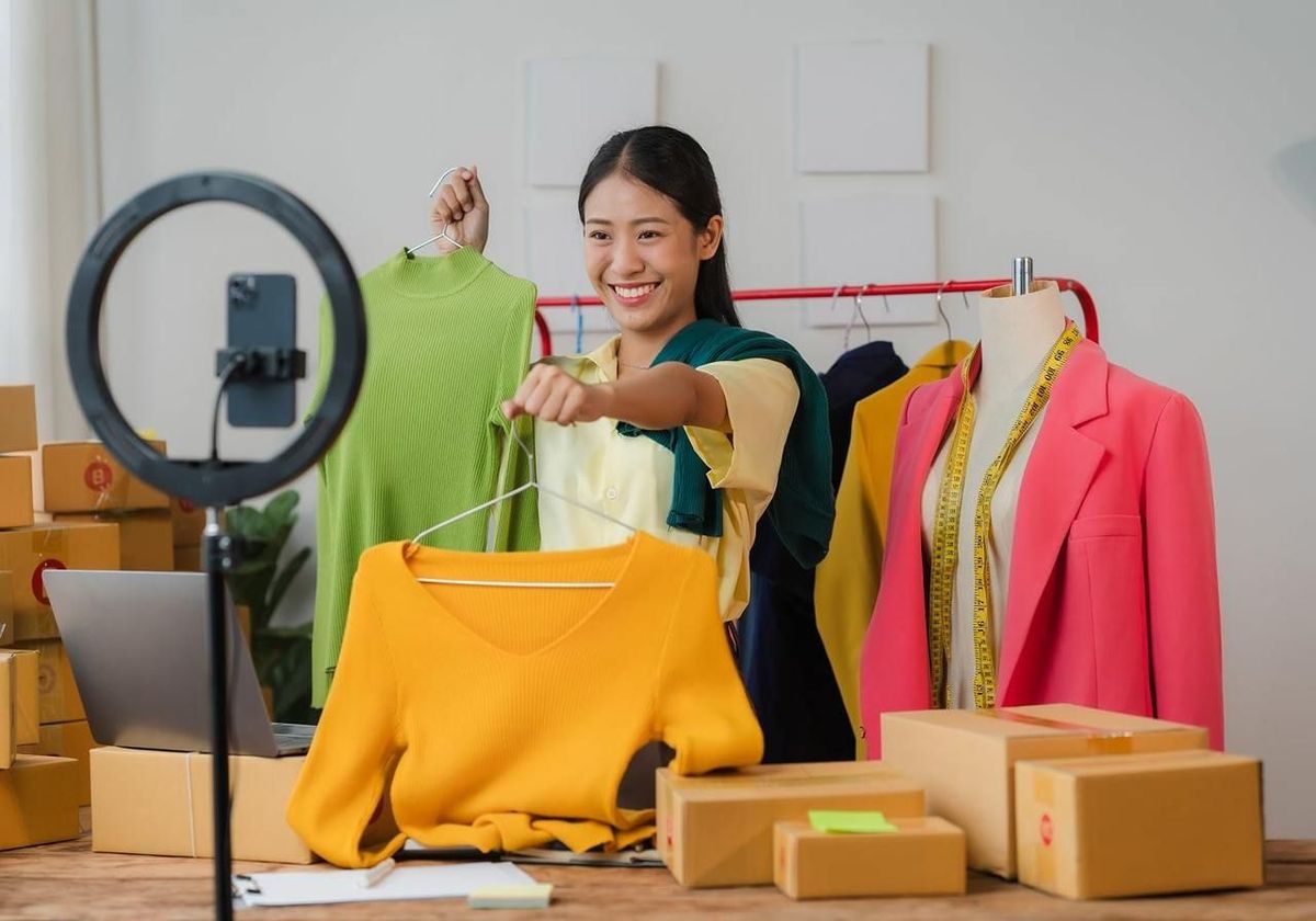 An online seller presenting clothes on a livestream, with parcels ready to ship